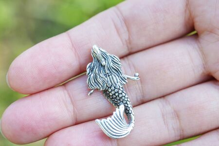 Sterling silver pendant in the shape of mermaid on female handの写真素材