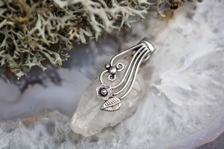 Fashionable ornamental crystal quartz silver decoration pendant on grey agate backgroundの写真素材