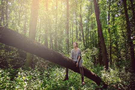Young woman sitting on the tree and enjoying nature around herの写真素材