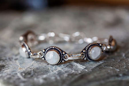 Beautiful female bracelet with moon stone on neutral rocky background