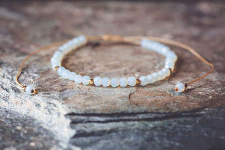 Rose quartz gemstone beautiful bracelet on grey rocky background
