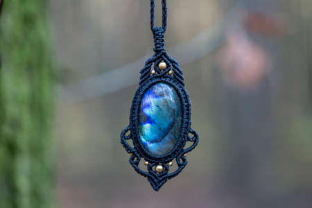 Mineral gemstone ornamental pendant on blury forest background