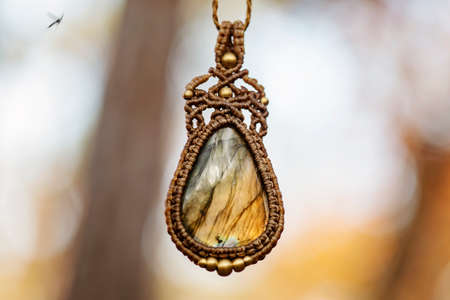 Mineral rose quartz gemstone ornamental pendant on blury forest backgroundの写真素材