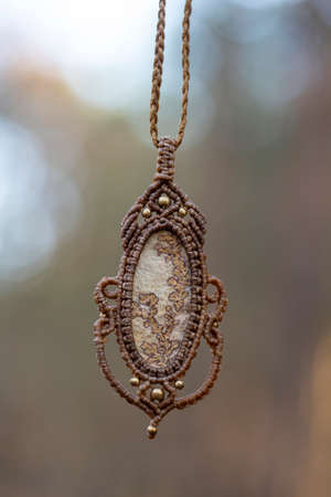 Mineral gemstone ornamental pendant on blury forest backgroundの写真素材