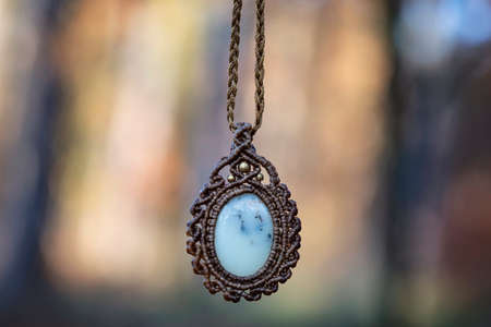 Mineral rose quartz gemstone ornamental pendant on blury forest background