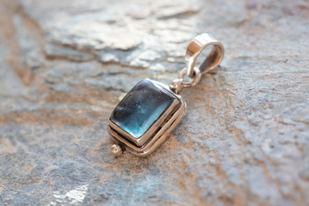 Close up of silver pendant with apatite gemstone on rocky grey backgroundの写真素材