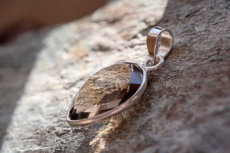 Sterling silver pendant with mineral lapis lazuli gemstone on rocky backgroundの写真素材