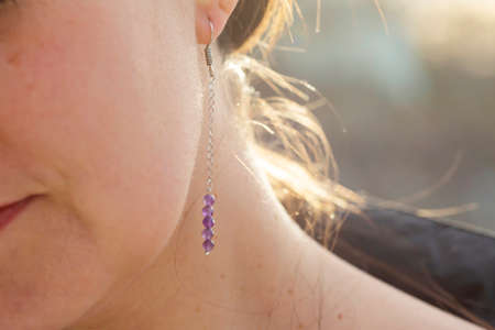 Female ear wearing long amethyst mineral stone earringの写真素材
