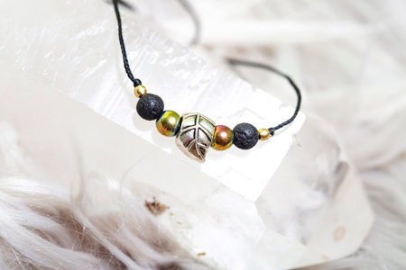 Fashionable mineral bead bracelet on black string on bright natural background