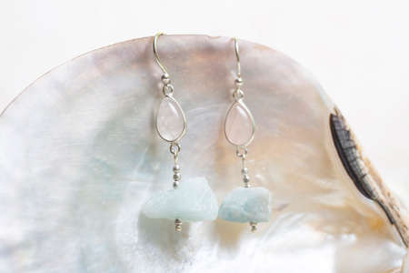 Decorative white cup with stone mineral earrings on white backgroundの写真素材