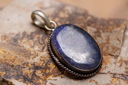 Silver metal mineral stone pendant on rocky backgroundの写真素材