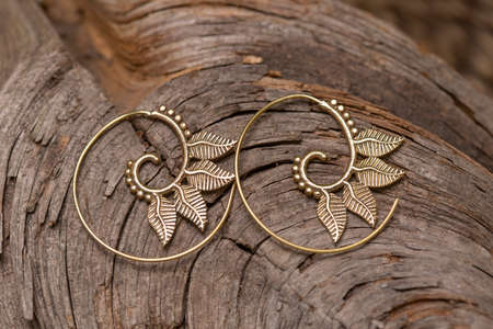 Ornamental brass metal earrings on natural backgroundの写真素材
