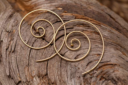 Ornamental brass metal earrings on natural backgroundの写真素材