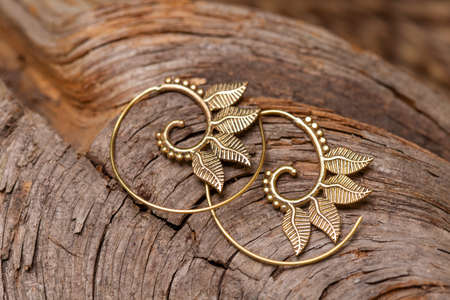 Ornamental brass metal earrings on natural backgroundの写真素材
