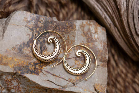 Ornamental brass metal earrings on natural background