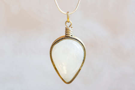 Mineral moon stone sterling silver simple pendant on neutral backgroundの写真素材