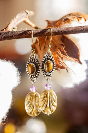 Beautiful earrings with amethyst and glass bead, hanging on natural backgroundの写真素材