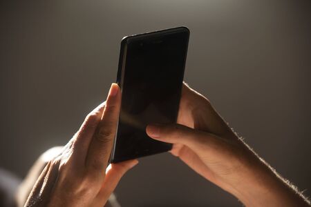 A young woman chatting with her smart phone at home. Photo with Horizontal Screen Orientationの写真素材