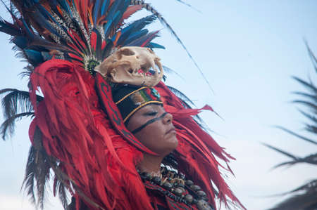 Close up unknown Mayan woman with traditional costume with feather headdress and a skull on her forehead - she dances in a tribal dance.のeditorial素材