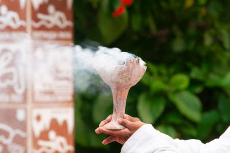 Young Mayan man holds in his hands a brazier lit with Copal smoke - Ancient Mayan tradition of purification and meditation, Mexico, Americaの写真素材