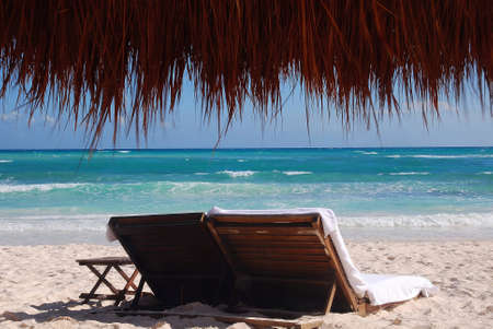 Empty beach loungers on a deserted tropical beach with natural straw and wood umbrella, Cancun, Mexicoのeditorial素材