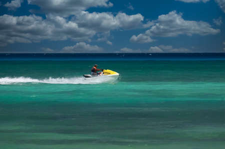 A man is sitting on a speeding jetski in Playa del Carmen, Mexico. Jetsky near a tropical beachのeditorial素材