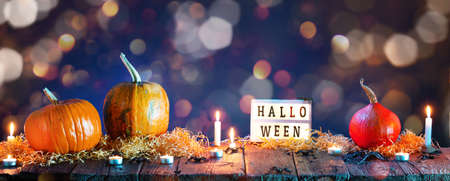 Halloween background. Pumpkins and burning candles on wooden tableの写真素材