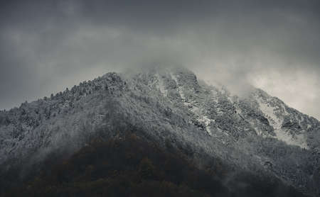Mysterious snow capped mountain with dramatic cloudy skyの写真素材