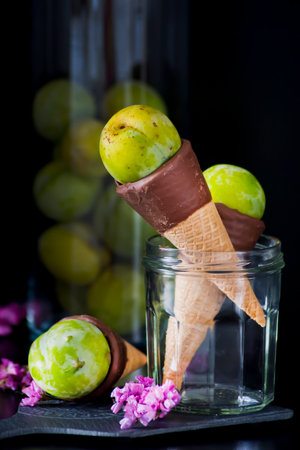 Glass jar with chocolate cones and green plums