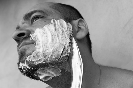 Man shaves his beard with a knifeの写真素材