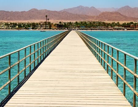 Panoramic image of a wooden bridge in the sea.