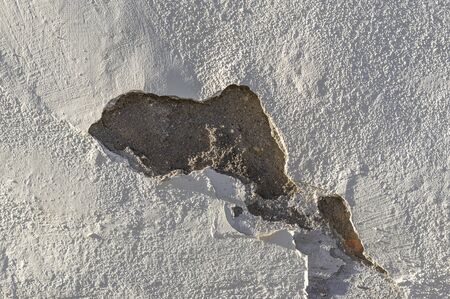 Plaster and paint clog, structural damage, water damage or frost damage to bright building wall in...