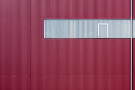 Modern factory facade clad with red elements and a band of lightの写真素材