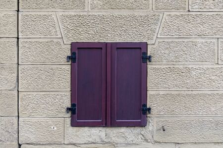 Beautiful idyllic light facade made of sandstone with a strong, burgundy shutter