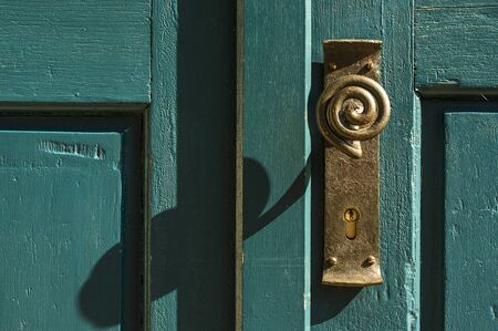 old brass door knob with looped handle on green wooden doorの写真素材