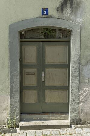 green wooden door with cassettes in old walls with slanted wallsの写真素材