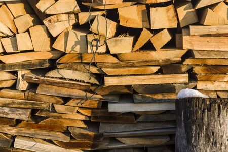 Wood stack of neatly stacked firewood and small wood to dry for firewood, firewood, raw material, wood rental with snow remains and chopping blockの写真素材