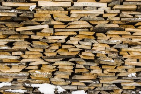 Wood stack of neatly stacked firewood and small wood to dry for firewood, firewood, raw material, wood rental with snow remainsの写真素材