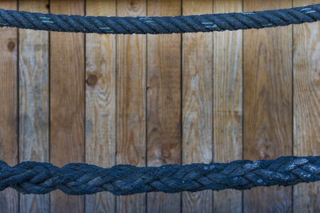 thin blue rope as a handrail in the upper and thick rope in the lower third. Wooden wall in the background with selective sharpnessの写真素材