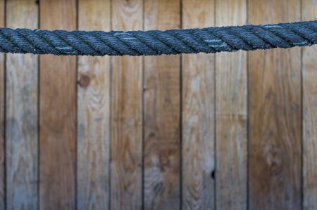 blue rope as a handrail in the upper third. Wooden wall in the background with selective sharpness