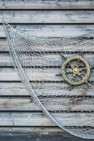 nostalgic ship wooden steering wheel with fishing net attached to wooden wall as decoration