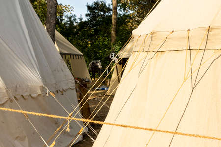 Reenactment of a medieval scene against the historical backdrop of an old city wall, village with tents of various designs with details of fabrics and pegs, ropes and bracing, view of tentsのeditorial素材