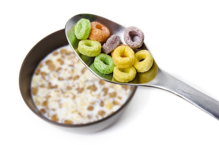 Close up of a spoon above a bowl with cereals and milk, isolated on white background