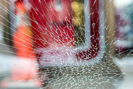 Cracked Shop Window Glass looking like a spider web, with red backgroundの写真素材