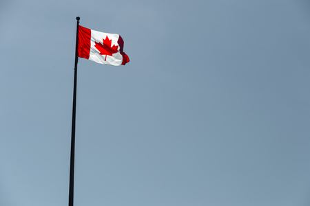 Canadian flag waving over pale blue skyの写真素材