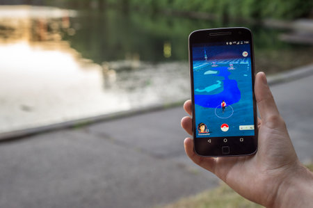 Montreal, CA - August 7, 2016: Closeup of a man playing Pokemon Go on a smart phone at sunset. Pokemon Go is a virtual reality game released in July 2016.のeditorial素材