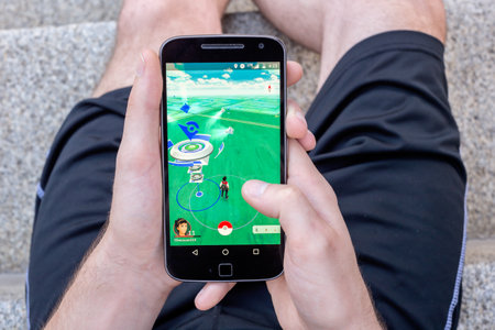 Montreal, CA - August 7, 2016: Closeup of a man playing Pokemon Go on a smart phone. Pokemon Go is a...
