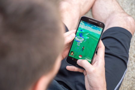 Montreal, CA - August 7, 2016: Closeup of a young man playing Pokemon Go on a smart phone. Pokemon...