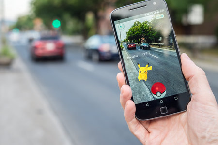 Montreal, CA - August 11, 2016: Closeup of a man playing Pokemon Go on a smart phone. Pokemon Go is...