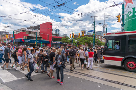 Dundas and Spadina corner in Toronto with people walking in the crosswalk and CN tower in the backgroundのeditorial素材